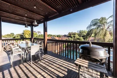 a grill on a deck with a table and chairs at Fralande Self Catering Units in Pretoria