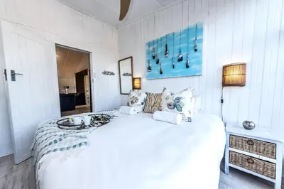 a white bedroom with a large white bed with pillows at Fralande Self Catering Units in Pretoria
