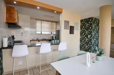 a kitchen with white chairs and a white counter at Unit 406 at Menlyn Place in Pretoria