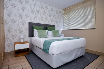 a bedroom with a large bed with green pillows at Unit 406 at Menlyn Place in Pretoria