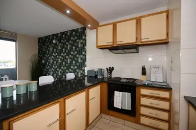a kitchen with wooden cabinets and a black counter top at Unit 406 at Menlyn Place in Pretoria
