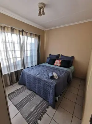 a bedroom with a blue bed and a window at Apartment@VillaVel in Midrand