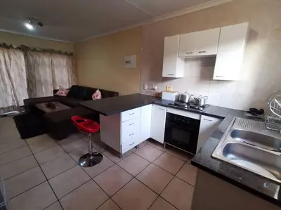 a kitchen and living room with a couch and a table at Apartment@VillaVel in Midrand