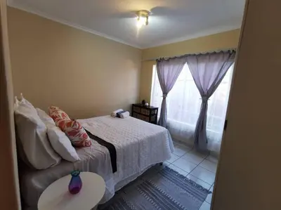 a bedroom with a bed with a table and a window at Apartment@VillaVel in Midrand