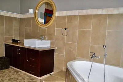 a bathroom with a tub and a sink and a mirror at Ambonnay Terrace Guest House in Pretoria