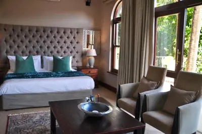 a bedroom with a bed and two chairs and a table at Ambonnay Terrace Guest House in Pretoria