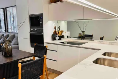 a kitchen with white cabinets and a table and a sink at Newton’s Place - Luxury styled 2 BD Apartment in Midrand