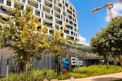 a building under construction with a crane and trees at Newton’s Place - Luxury styled 2 BD Apartment in Midrand