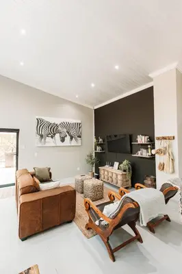 a living room with a couch and a zebra picture on the wall at Chawal stays @ Leguan in Marloth Park
