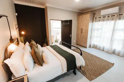 a bedroom with a large bed with a black headboard at Chawal stays @ Leguan in Marloth Park