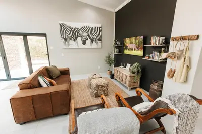 a living room with a couch and zebra prints on the wall at Chawal stays @ Leguan in Marloth Park