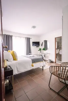 a bedroom with a bed and a chair in it at LilyRose Bed & Breakfast in Pretoria