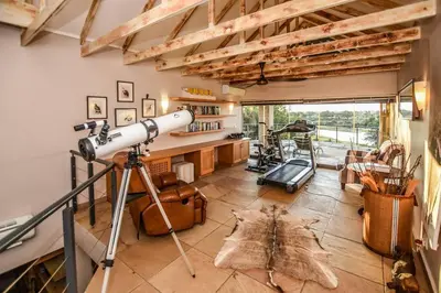 a telescope in a living room with a table at Impangele River Lodge in Hectorspruit