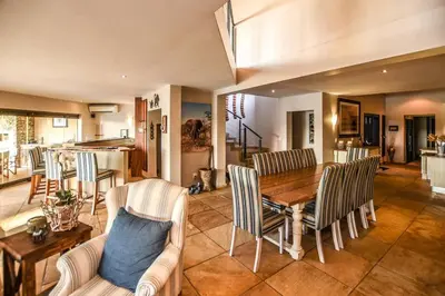 a living room with a wooden table and chairs at Impangele River Lodge in Hectorspruit