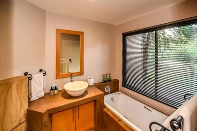 a bathroom with a sink and a bath tub at Impangele River Lodge in Hectorspruit