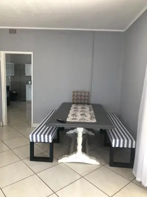 a dining room table with two chairs and a bench at Kieron's Cottage in Lydenburg
