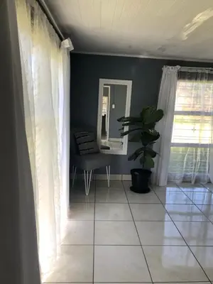 a living room with a potted plant and a mirror at Kieron's Cottage in Lydenburg
