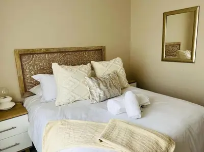 a bedroom with two beds with white pillows and a mirror at Wanderlust 2-bedroom Apartment in Centurion