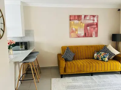a living room with a yellow couch and a kitchen at Wanderlust 2-bedroom Apartment in Centurion