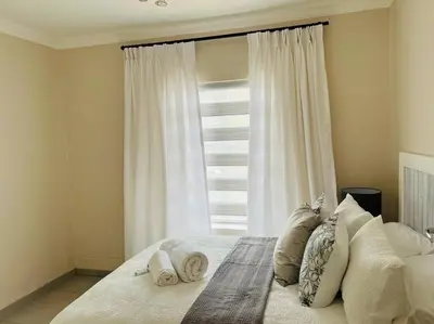 a bedroom with a bed with pillows and a window at Wanderlust 2-bedroom Apartment in Centurion