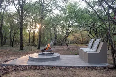 a fire pit and two chairs in a park at Wild Honey Studio in Marloth Park