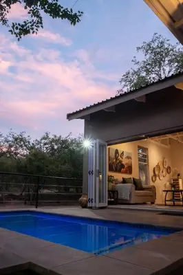 a villa with a swimming pool at night at Wild Honey Studio in Marloth Park
