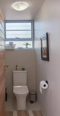 a bathroom with a white toilet and a window at Wild Honey Studio in Marloth Park