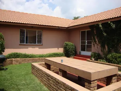 a house with a stone table in the yard at Gateway Guesthouse in Benoni