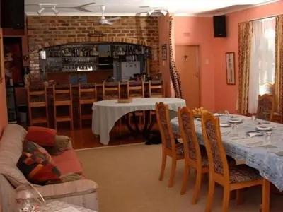 a dining room with a table and chairs and a room with at Gateway Guesthouse in Benoni