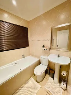 a bathroom with a toilet and a sink and a bath tub at A Warm 3 bed Townhouse in a secure complex in Witbank
