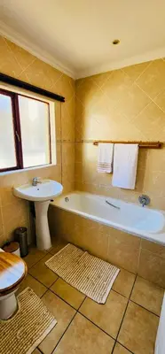 a bathroom with a tub and a sink and a toilet at A Warm 3 bed Townhouse in a secure complex in Witbank