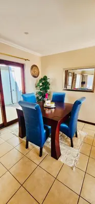 a dining room with a table and blue chairs at A Warm 3 bed Townhouse in a secure complex in Witbank