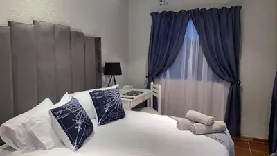 a bedroom with a white bed with blue pillows and a window at OR Tambo Stay Unit 2 in Boksburg