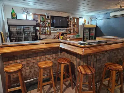 a bar with wooden stools in a room at Pietersburg Lodge in Polokwane