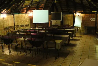 a large room with tables and chairs and a screen at Pietersburg Lodge in Polokwane