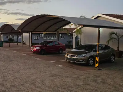 two cars parked in a parking lot next to a building at Pietersburg Lodge in Polokwane