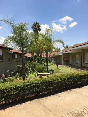 a row of houses with palm trees and a sidewalk at Pietersburg Lodge in Polokwane