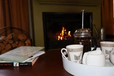 a table with cups of coffee on a table with a fireplace at Rawlingsons Country House in Dullstroom