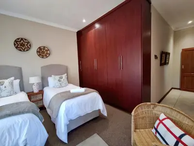 a bedroom with two beds and a large wardrobe at Rawlingsons Country House in Dullstroom