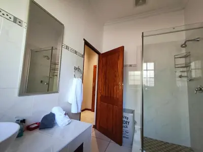 a bathroom with a shower and a sink and a mirror at Rawlingsons Country House in Dullstroom