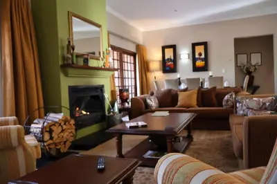 a living room with a couch and a fireplace at Rawlingsons Country House in Dullstroom