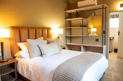 a bedroom with a large bed with white sheets and pillows at Buffelshuis Safari Camp in Golders Green