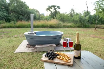 a table with a bottle of wine and a plate of food at Buffelshuis Safari Camp in Golders Green