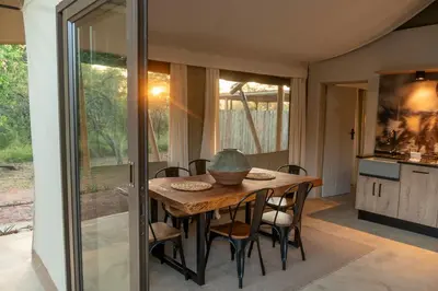 a kitchen and dining room with a table and chairs at Buffelshuis Safari Camp in Golders Green