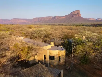 an aerial view of a house with mountains in the background at Buffelshuis Safari Camp in Golders Green