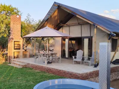 a patio with a table and an umbrella at Buffelshuis Safari Camp in Golders Green