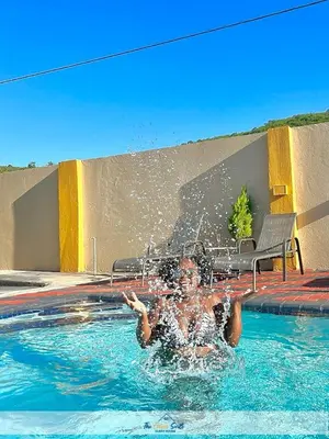 a woman is in a swimming pool with water at The Curve Suite Guest House in Nkowakowa