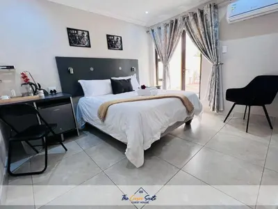 a bedroom with a bed and a table and chairs at The Curve Suite Guest House in Nkowakowa