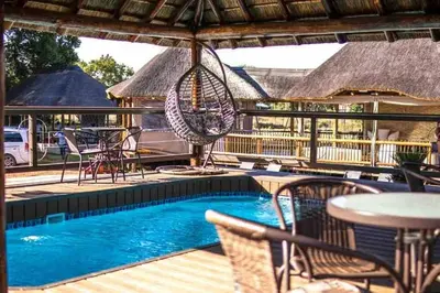 a swimming pool with a swing and a table and chairs at Falcon Lodge Bela Bela in Bela-Bela