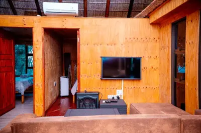 a living room with a fireplace and a tv on a wall at Falcon Lodge Bela Bela in Bela-Bela